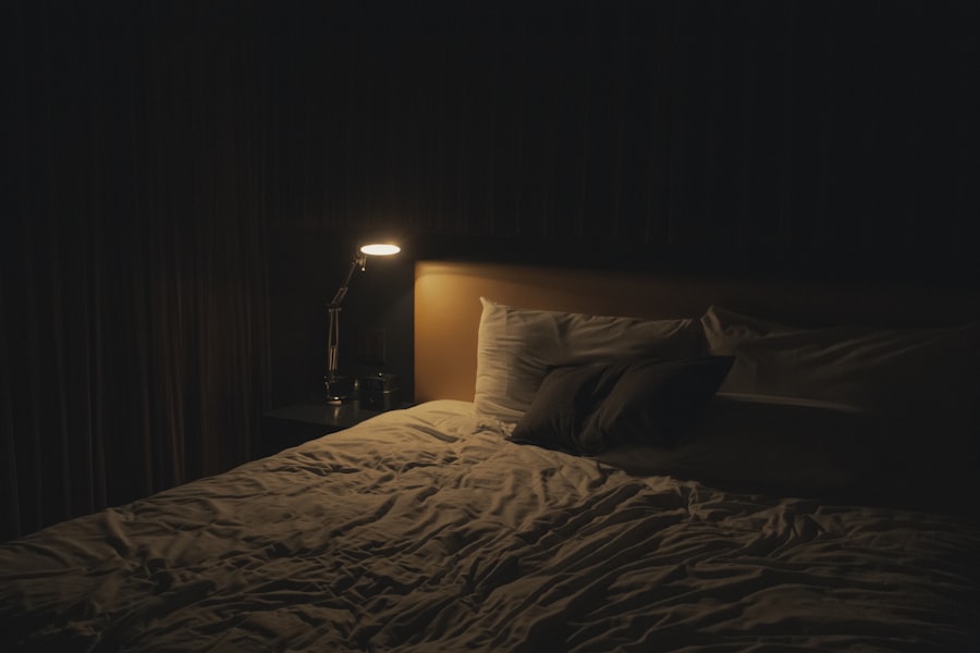 Bedside lamp glowing in a dark room beside a bed